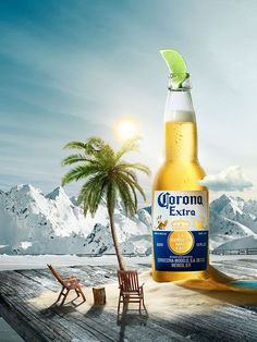 a bottle of corona beer sitting on top of a wooden table next to a palm tree