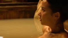 a woman sitting in a hot tub with her head turned to the side and looking off into the distance