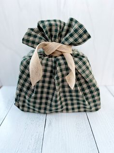 a green and white checkered bag with a bow on the front sitting on a wooden floor