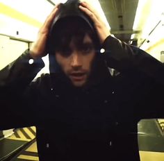 a man holding his head while standing next to an escalator