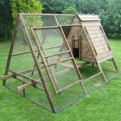 a large chicken coop in the middle of some grass