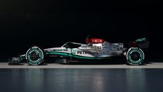 a white and green race car on display in a dark room with no one around it