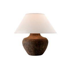 a lamp that is on top of a white table cloth and has a brown base with a white shade