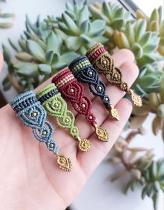 a hand is holding five rings made with beads and crocheted yarns on them