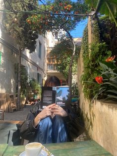 a person sitting at a table with a book in front of them and a cup of coffee