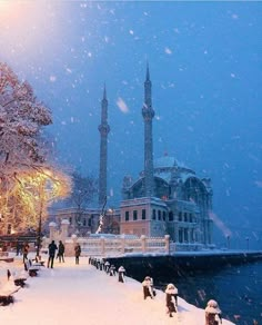 people are walking in the snow near a large building with two minalis on it