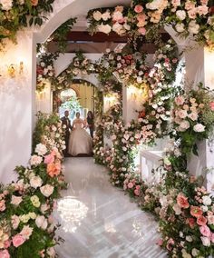 the bride and groom are walking down the aisle with flowers all around them on either side