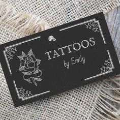 a black and white business card that says tattoos by emily on it with a rose in the middle