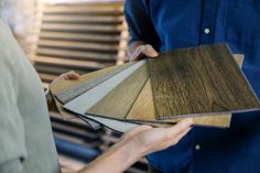 two men are holding samples of wood flooring