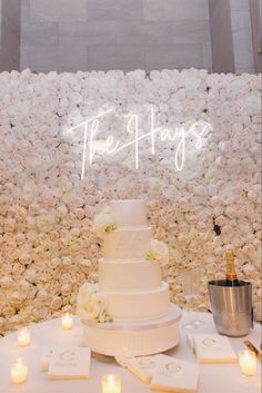 a white wedding cake sitting on top of a table next to candles and flowers with the word free hugs written above it