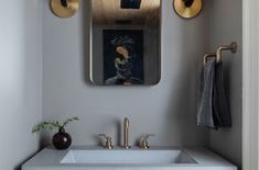 a bathroom sink sitting under a mirror next to a wall mounted faucet