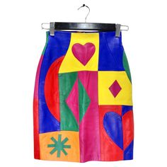 Introducing the Michael Hoban 1980s Multicolor Leather Pencil Skirt – a true vintage gem that transcends time with its vibrant personality and striking design. This statement piece is a celebration of boldness, featuring a kaleidoscope of multicolored leather panels adorned with playful geometric shapes, including hearts, diamonds, and stars. The skirt boasts a dynamic color block pattern that is a visual feast for the eyes. The combination of hues and geometric shapes creates a lively and energ 80s Leather Skirt Outfit, 80s Skirt Outfit, Cheap Retro Multicolor Mini Skirt, Retro Multicolor Relaxed Skirt, Retro Multicolor Pleated Skirt, Chanel Blouse, Vintage Multicolor Skirt, 80s Skirt, Vibrant Personality