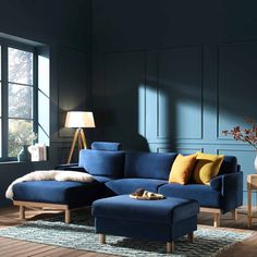 a living room with dark blue walls and wooden flooring, an ottoman is in the foreground