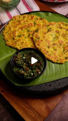 some food is on a green plate with sauces and a glass bowl next to it