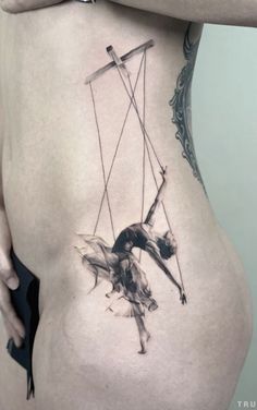 a woman's back with a tattoo on her stomach and the image of a man swinging