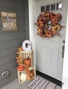 a front door with a fall wreath, pumpkins and other autumn decorations on it