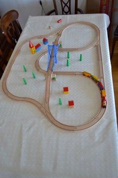 a toy train set sitting on top of a table next to a white cloth covered table