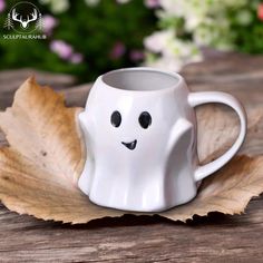 a coffee cup with a ghost face on it sitting on top of a wooden table