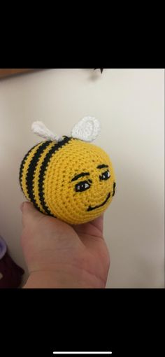 a crocheted bee with a smile on it's face is being held up