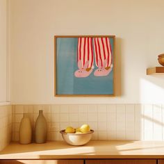 a bowl of lemons sits on a counter in front of a painting hanging above it