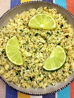 a bowl filled with rice and limes on top of a striped table cloth,