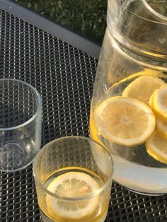 lemons and water are on the table next to a pitcher with some liquid in it