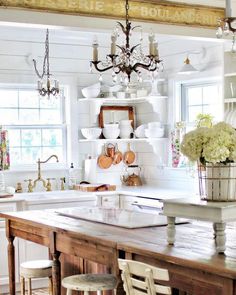 a kitchen with white walls and wooden table in front of the sink, chandelier