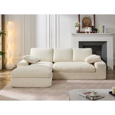 a white couch sitting on top of a wooden floor next to a fire place in a living room