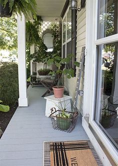 the front porch is decorated with plants and potted plants