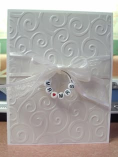 a close up of a card on a table with a ribbon around it and two name beads