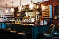 a bar with lots of bottles and lights hanging from it's ceiling, along with stools