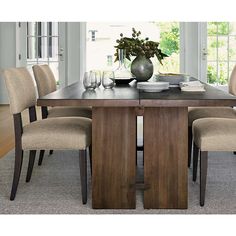 a dining room table with chairs and a vase filled with flowers on top of it