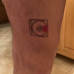 a man's leg with a small circle tattoo on the side of his leg