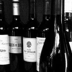 several bottles of wine are lined up on a shelf in a black and white photo