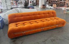 an orange couch sitting on top of a cement floor