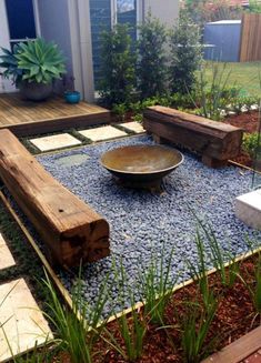 a wooden bench sitting on top of a gravel covered ground next to a garden area