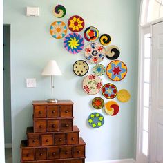 the wall is decorated with many colorful plates on it's face and has a lamp next to it