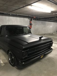 an old black truck parked in a parking garage