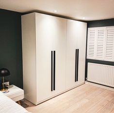 a bedroom with green walls and white cupboards on the wall next to a bed