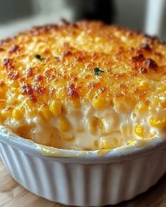 a casserole dish with corn and cheese in it on a wooden counter top