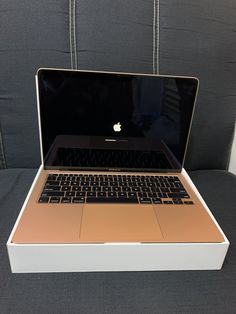 an open laptop computer sitting on top of a white box next to a gray couch