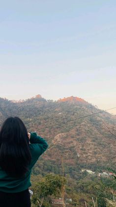 a woman standing on top of a lush green hillside