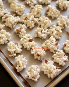 the cookies are covered in white frosting and chopped walnuts on a baking sheet