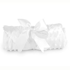 a white pillow with a bow on the top and ribbon at the bottom, sitting on a white surface