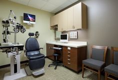 a room with two chairs, a desk and a monitor on the wall in front of it