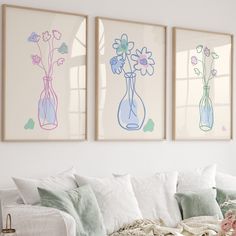 three vases with flowers in them are hanging on the wall above a white couch