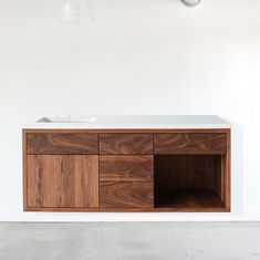 a white sink sitting on top of a wooden cabinet next to a light hanging from the ceiling