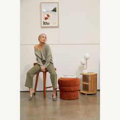 a woman sitting on top of a wooden chair next to a small table and stool