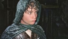 a young man wearing a green scarf around his neck and hood covered in snow while looking at the camera