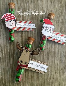 three christmas candy sticks with santa claus and reindeer on them sitting on a wooden table